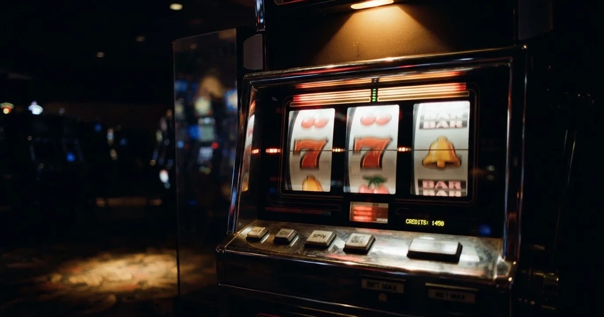 Rolos luminosos de uma slot machine numa sala escura, em grande plano — cassino grátis em portugal